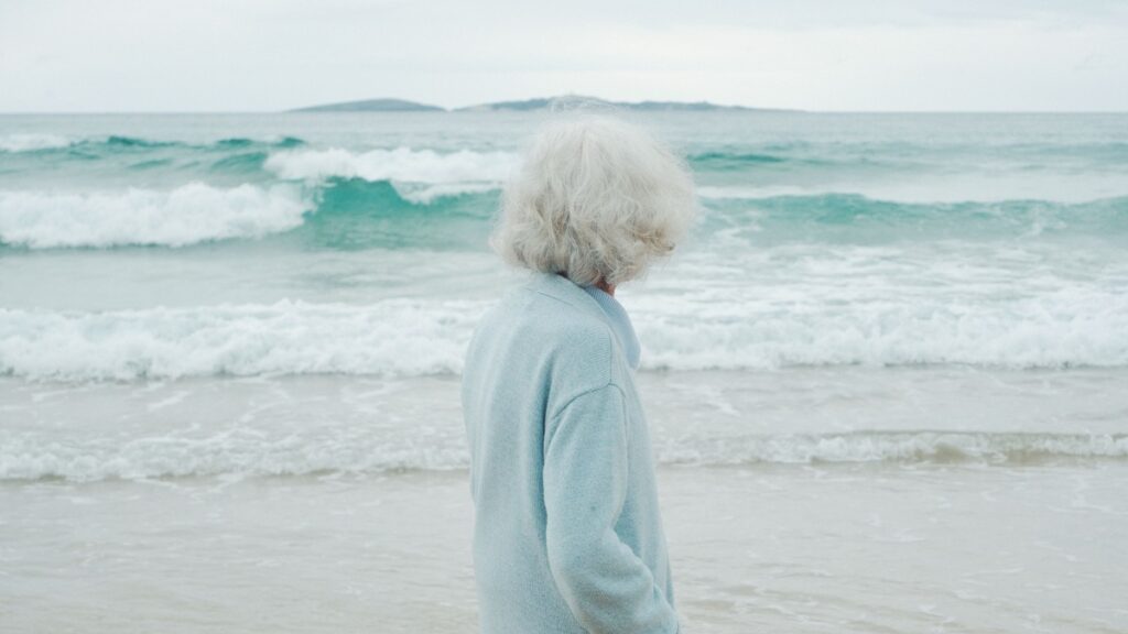 Older woman standing beside the ocean at Narooma on the New South Wales coast.